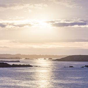 Coucher De Soleil aux tons mauve vu de Saint Lunaire. Le panorama offre des vues sur la Manche, l'île Agot de Saint-Briac-sur-Mer, la Baie de Lancieux et le clocher de Saint-Jacut de la Mer. Crédit photo : Studio Jezequel