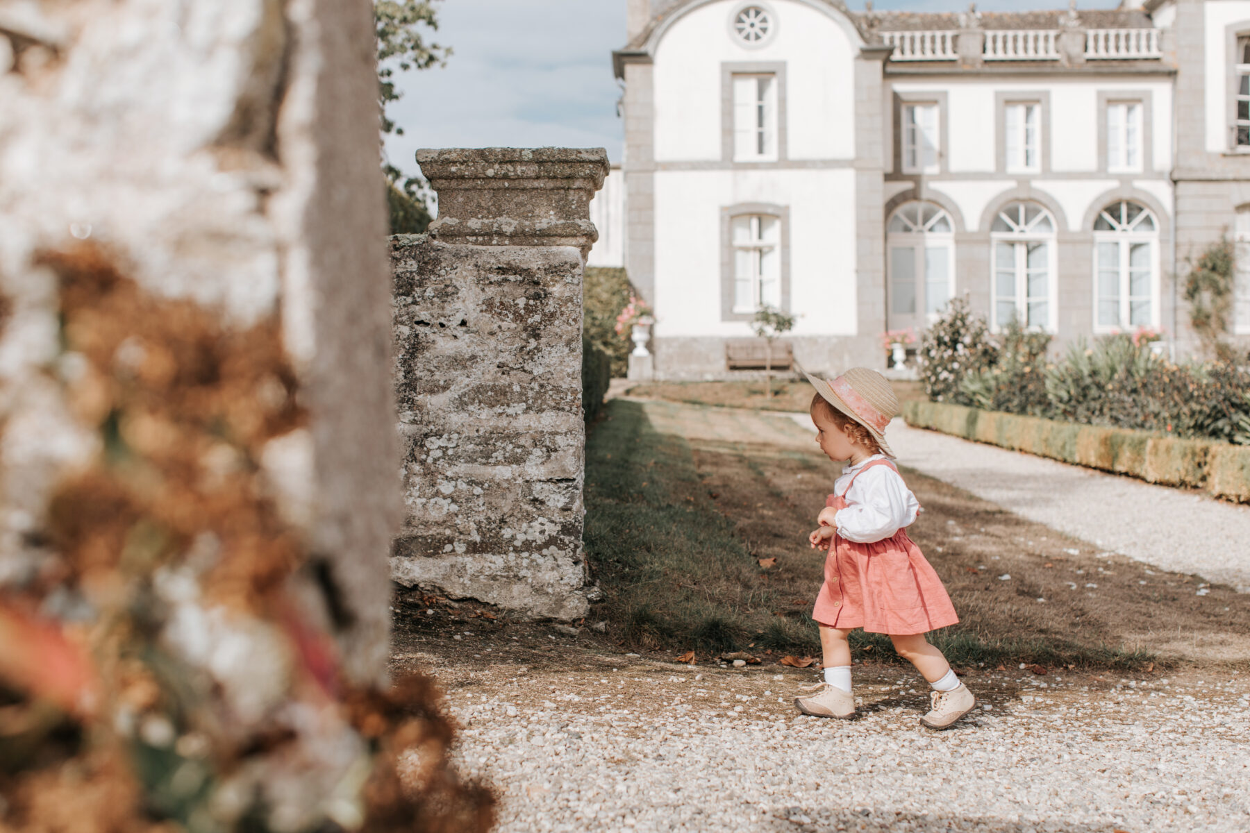 Une petit fille en robe rose et chapeau de paille se balade dans les allées du jardin de la Malouinière Du Montmarin à Pleurtuit, sur les bords de l'estuaire de la Rance, en Bretagne.