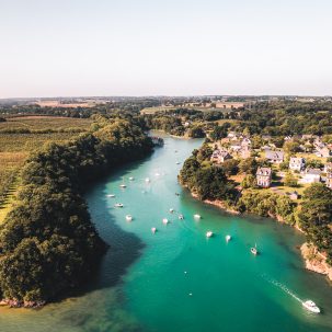 L'Anse Des Grandes Rivières à La Richardais vue du ciel. Un bras de la Rance aux couleurs émeraude, entourée de champs à sa gauche et du village de la La Richardais à sa droite. Un endroit paisible à découvrir sur les bords de la Rance à pied, à vélo ou en paddle ou kayak. Crédit photo : Lezbroz.