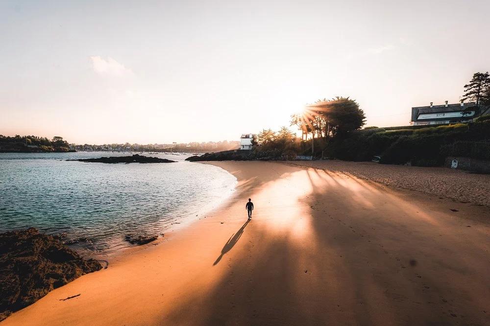 Balade Nocturne sur la plage A Lancieux. Un homme se promène au coucher du soleil sur le bord de l'eau.