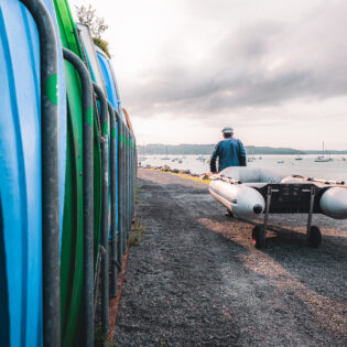Un homme tire une annexe de bateau juqu'à la plage de Garel au Minihic Sur Rance.