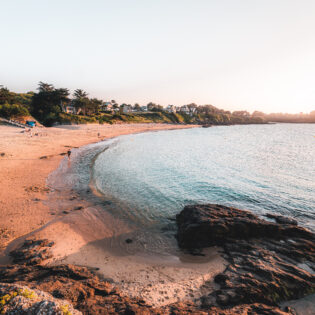 Un homme se promène sur la Plage De La Fourberie à Saint Lunaire au coucher du soleil. Une plage bien orientée à proximité de Dinard.