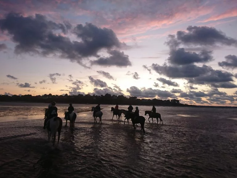 Balade à cheval sur la plage en baie de Lancieux avec le Ty haras. Une activité équestre à pratiquer en juillet et août sur la Côte d'Émeraude.