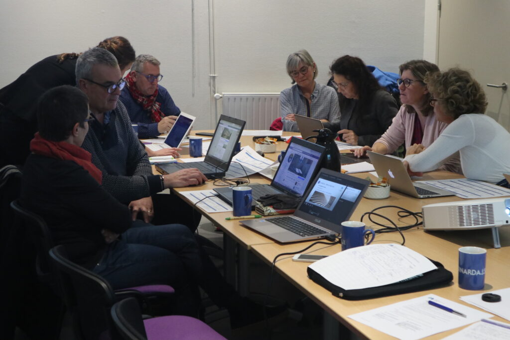 Atelier Facebook à Dinard. Un groupe de professionnels travaille ensemble dans une salle de réunion à Dinard, utilisant des ordinateurs portables, concentrés sur une discussion collaborative. Les ateliers numériques