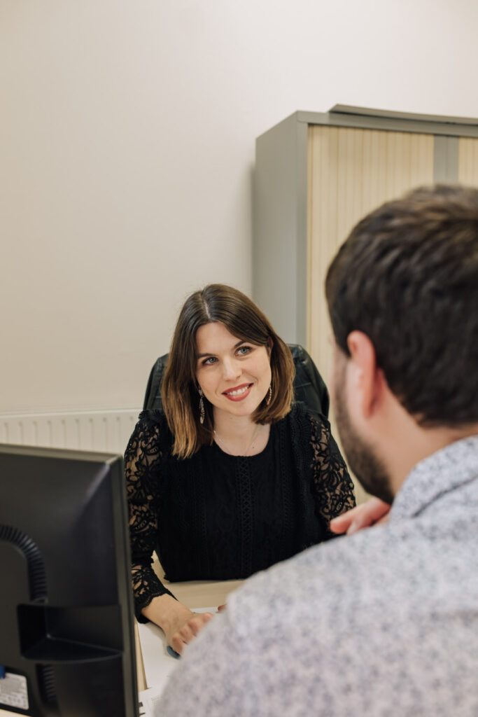 La référente des partenariats échange avec un professionnel du tourisme. Elle lui expose les supports de communication.